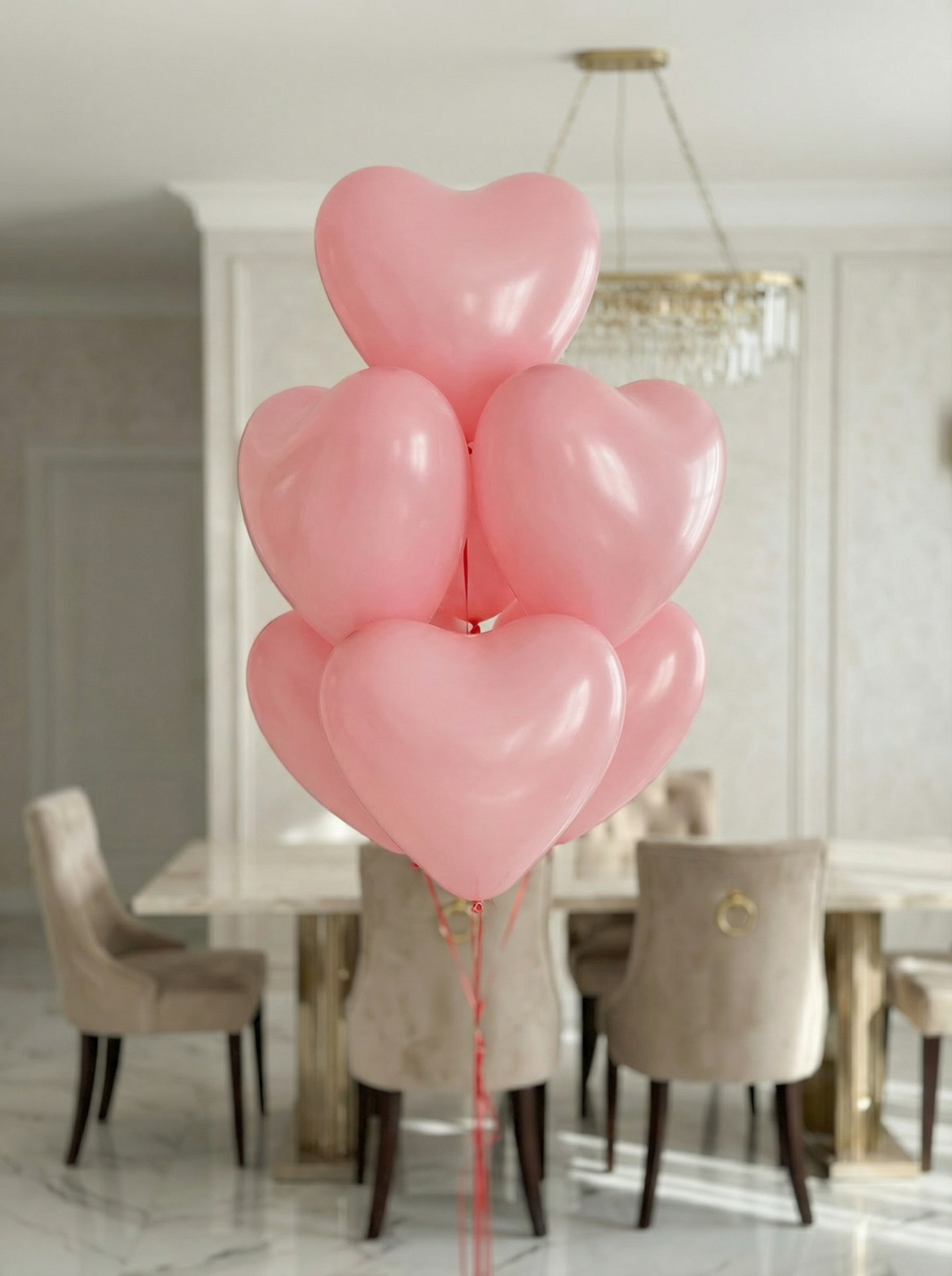 Букет из нежно-розовых латексных шаров в форме сердца с лентами в светлом интерьере.